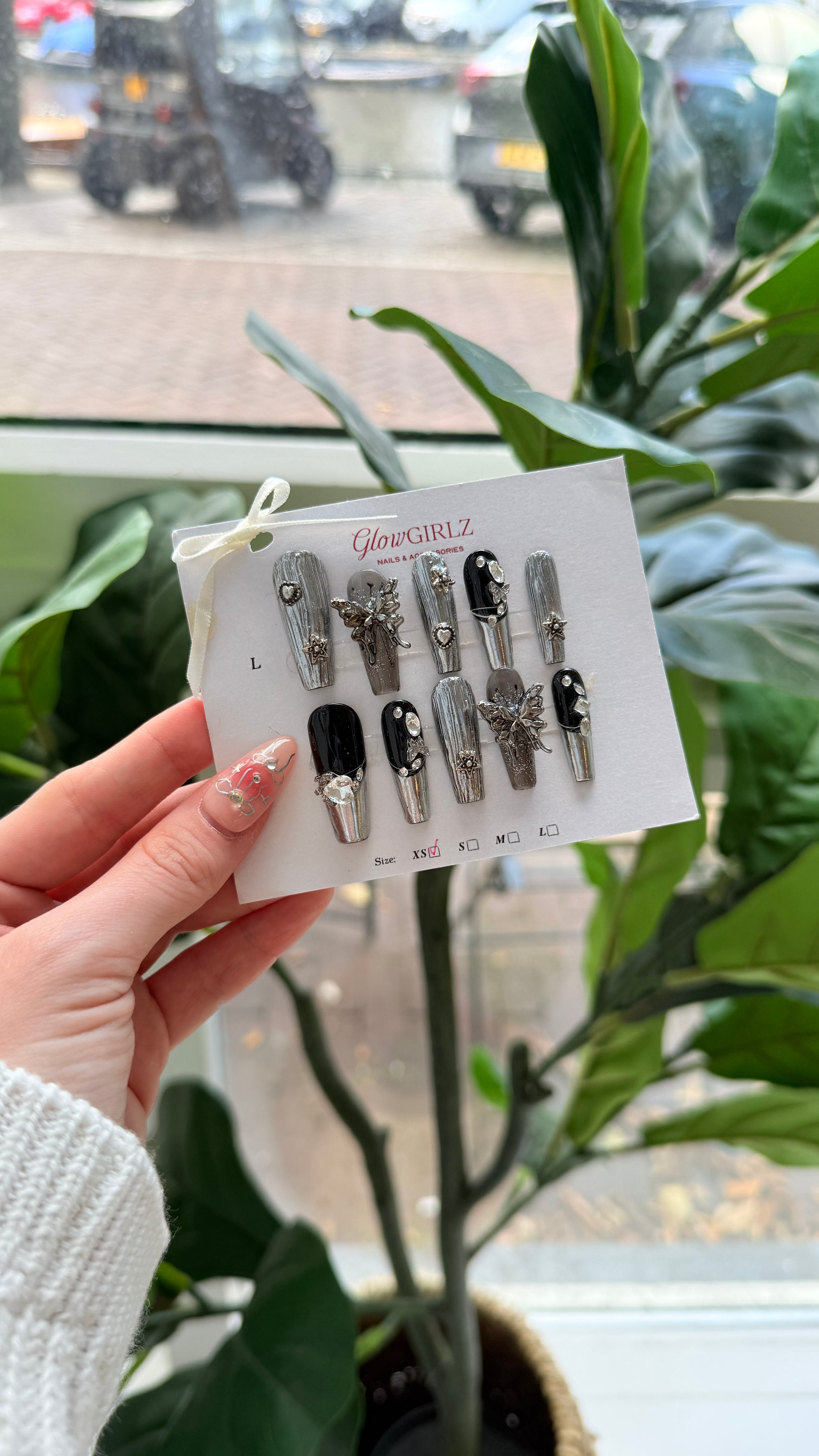 Hand holding a card with nails against a blurred indoor background